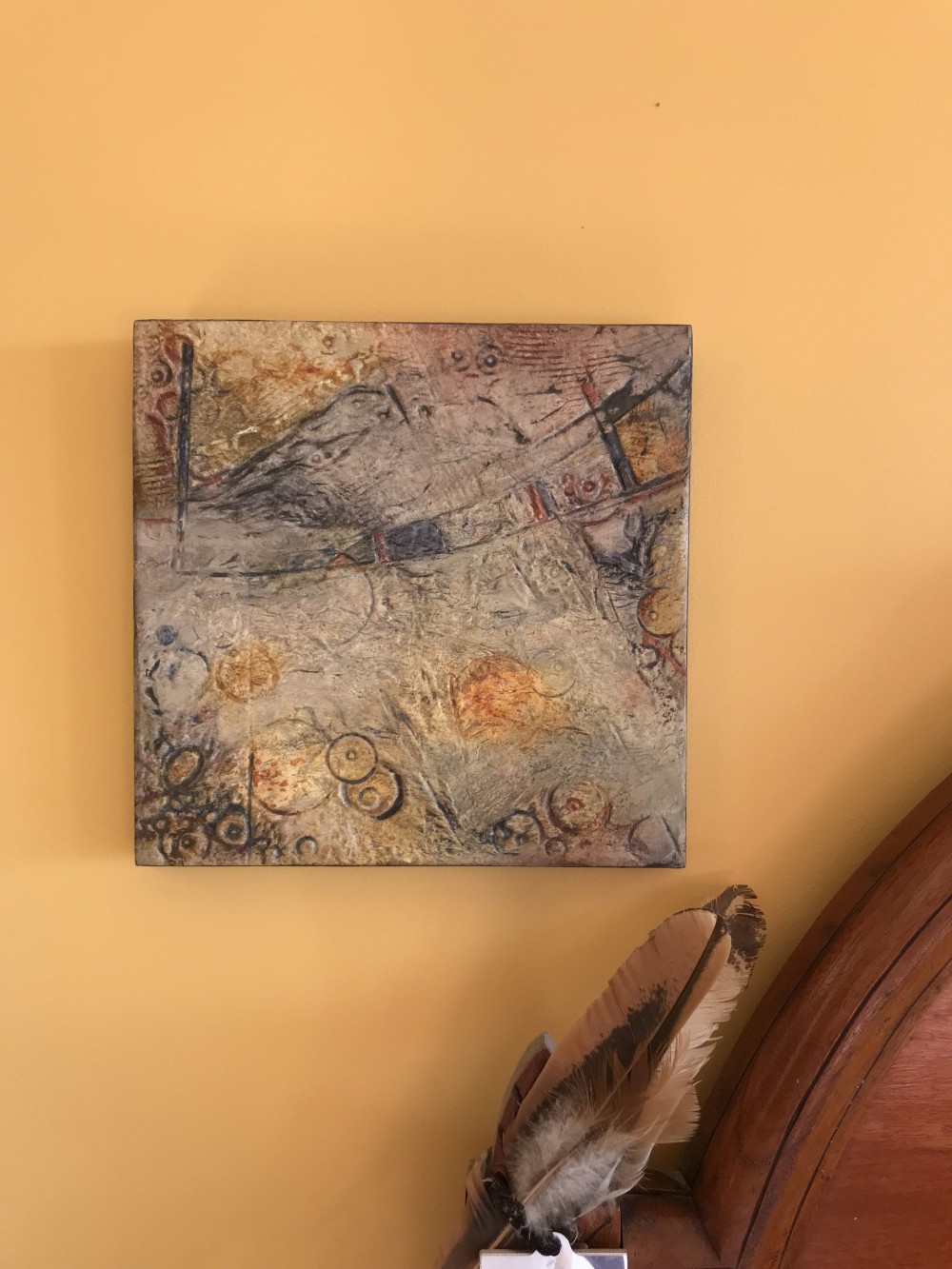 Square abstract panel in ochre, rust and grey with heavy texture, incised circles and a diagonal band across the upper half