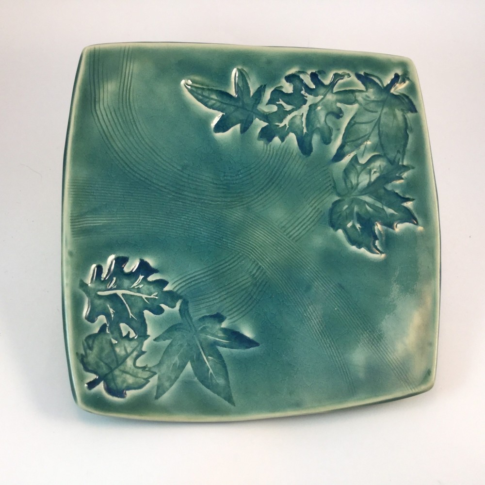 Square hand-built plate glazed in turquoise, with maple and oak leaves pressed into the surface at two opposite corners
